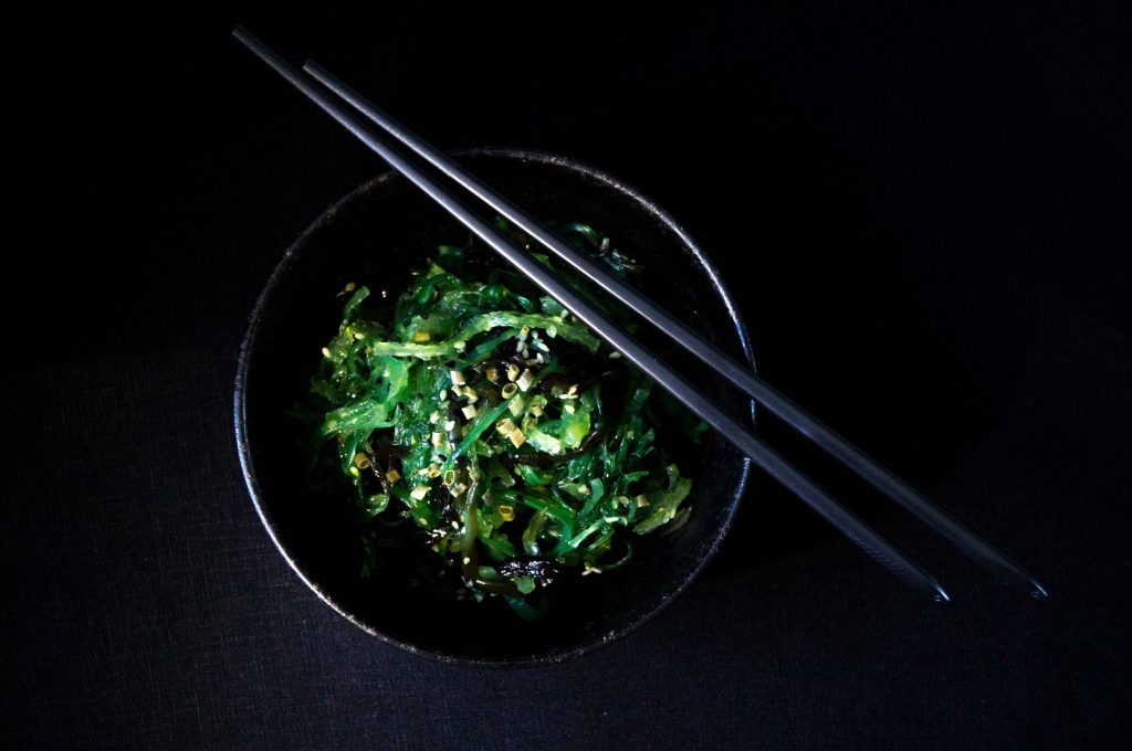 vegetable salad in black bowl with chopsticks